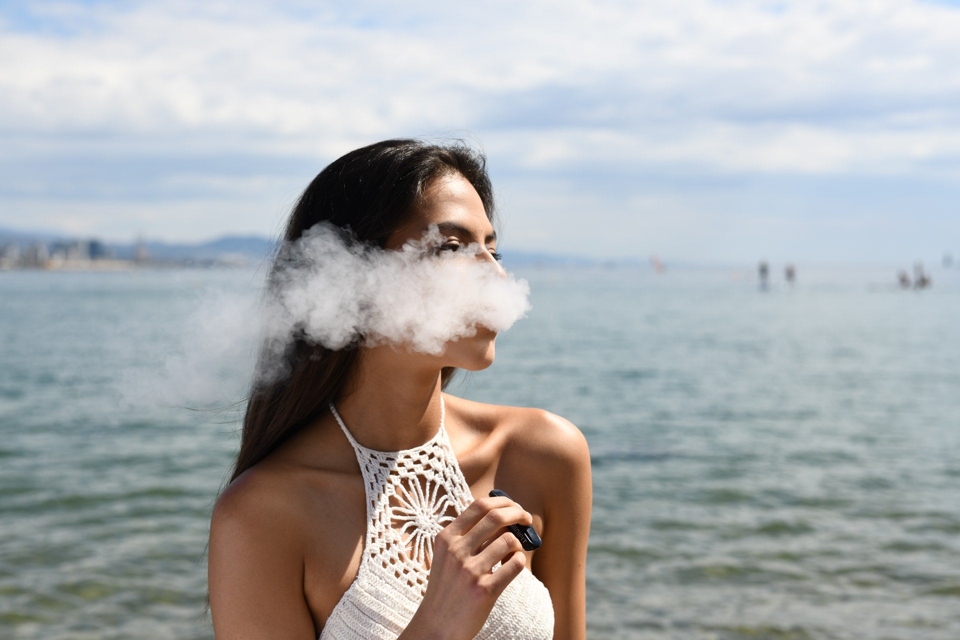 Attractive young woman smoking weed vape pen at the beach.