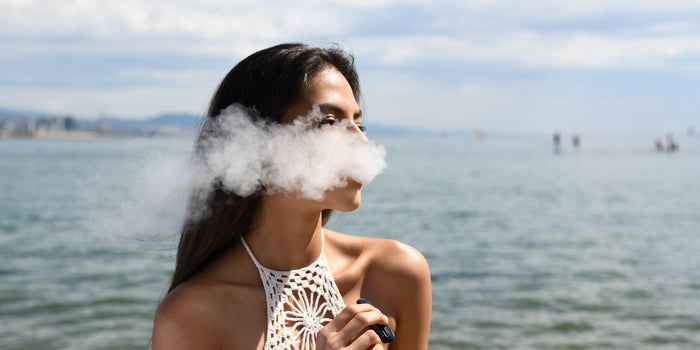 Attractive young woman smoking weed vape pen at the beach.