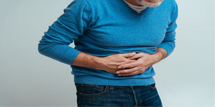 Elderly man suffering from IBD disease. He is holding his stomach with both hands.